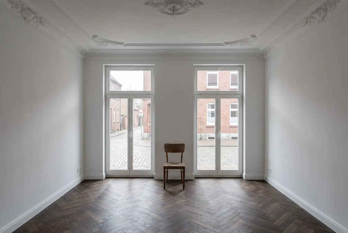 Fertig sanierte Altbauwohnung mit weißen Wänden, restaurierter Stuckdecke und neuem Fischgrätparkett